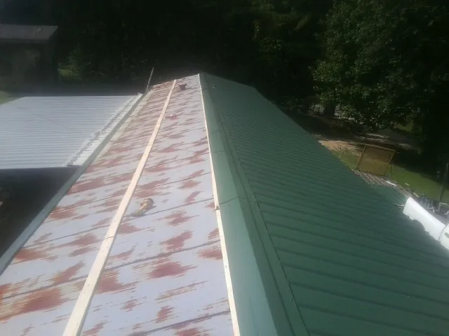 Old rusted panels beside newly installed green metal roofing — Wind Damage Roof Repair by Roofing Brothers in Frankford