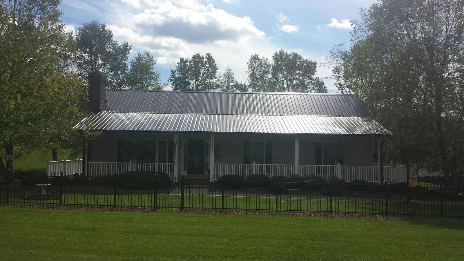 Gray metal roof on a brick ranch with a full width front porch — Gutter Guard Installation work by our crew in Frankford