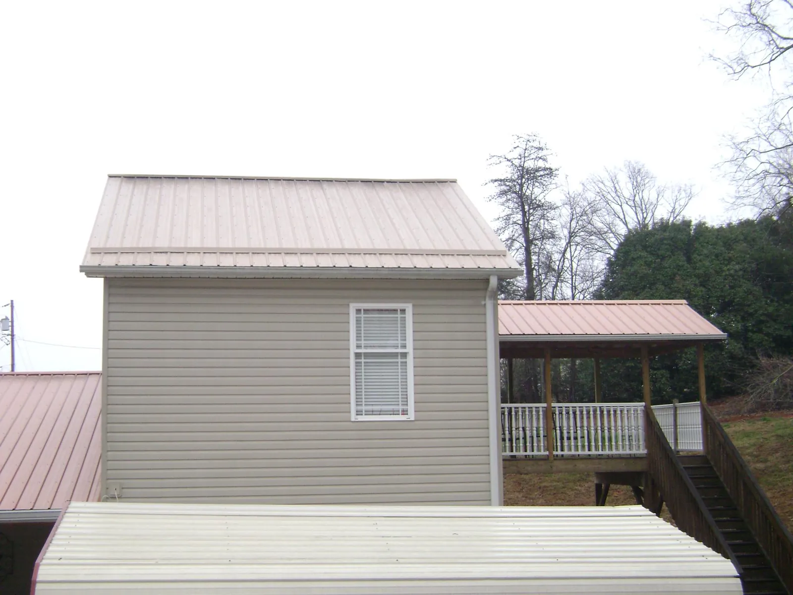 Tan metal roofs on a two story addition and attached porch, from a Roof Replacement job in Frankford